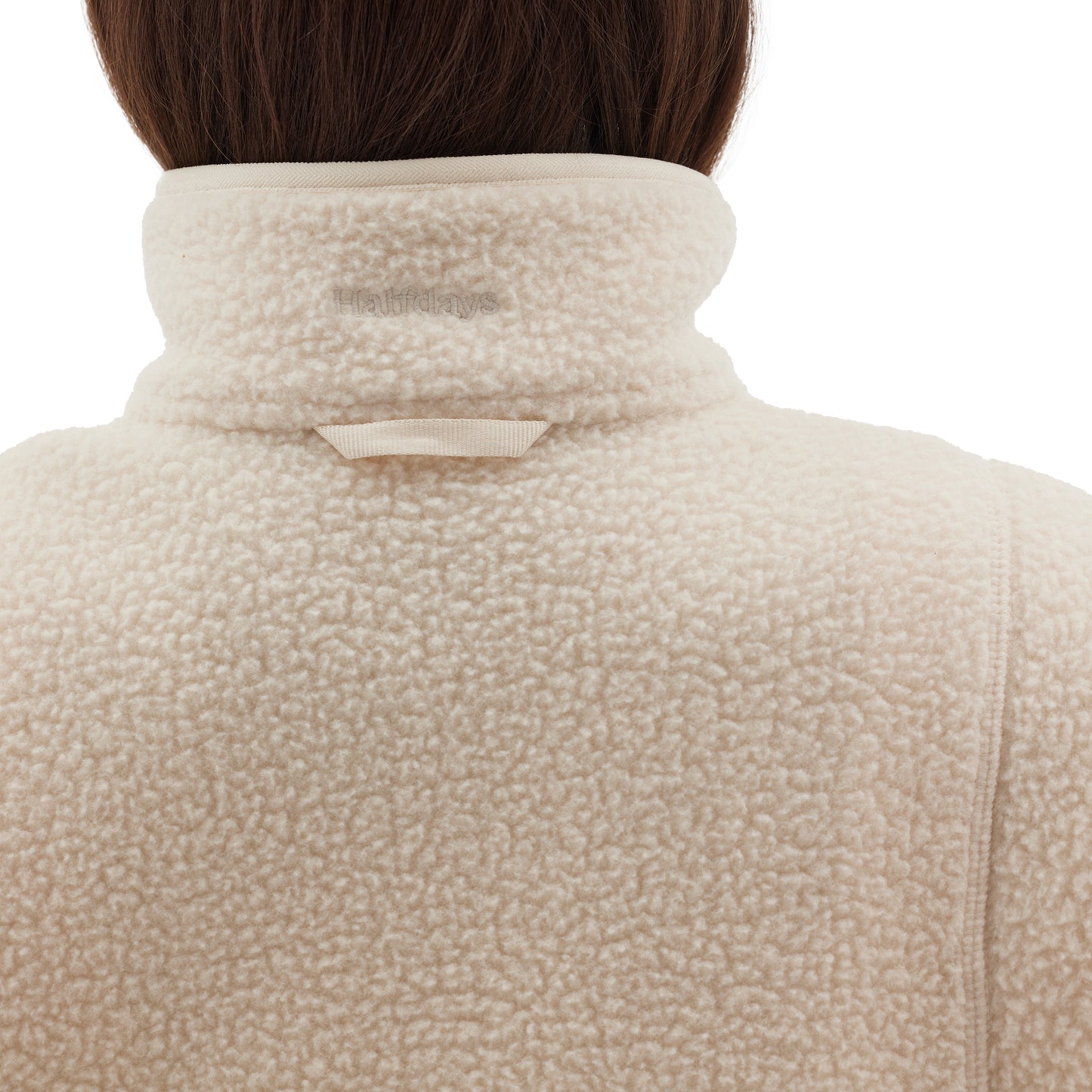 Rear view of a person wearing the Pieper Fleece by Halfdays, a cream-colored quarter-zip jacket with the collar up, highlighting its performance durability.