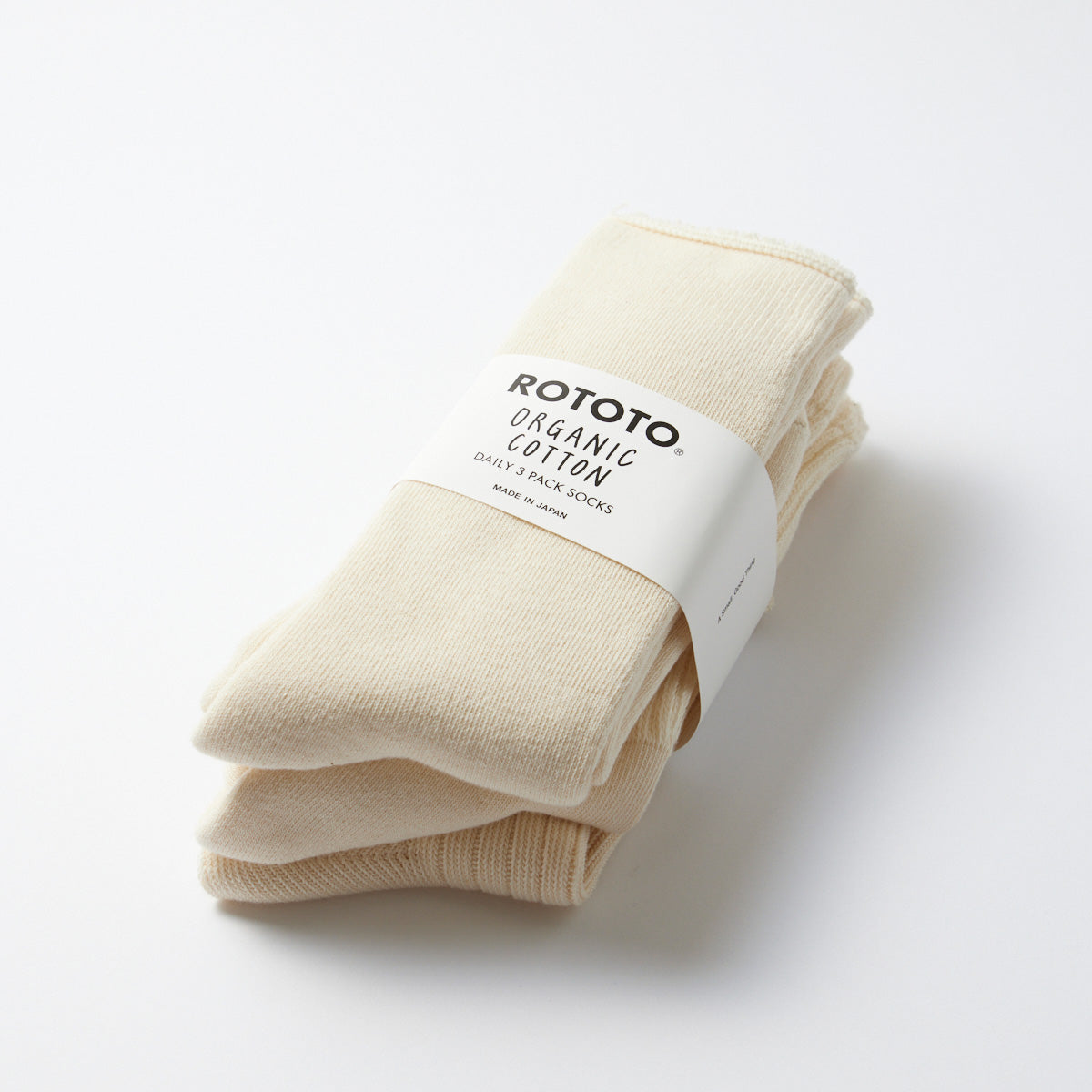 A pair of ecru ribbed crew socks folded with a label that reads "RoToTo Organic Daily 3 Pack Ribbed Crew Socks.