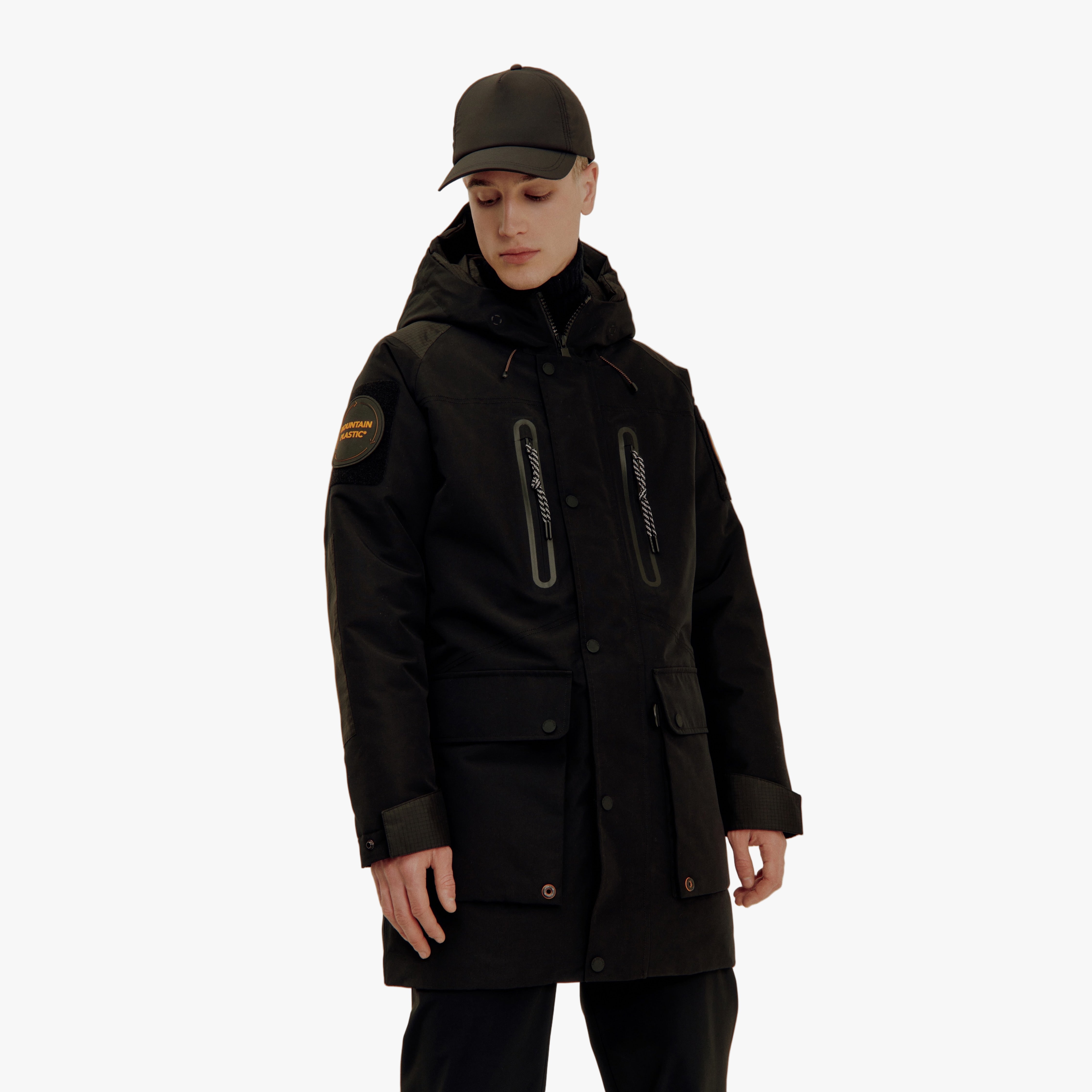 Person wearing a black coat and cap on a light gray background