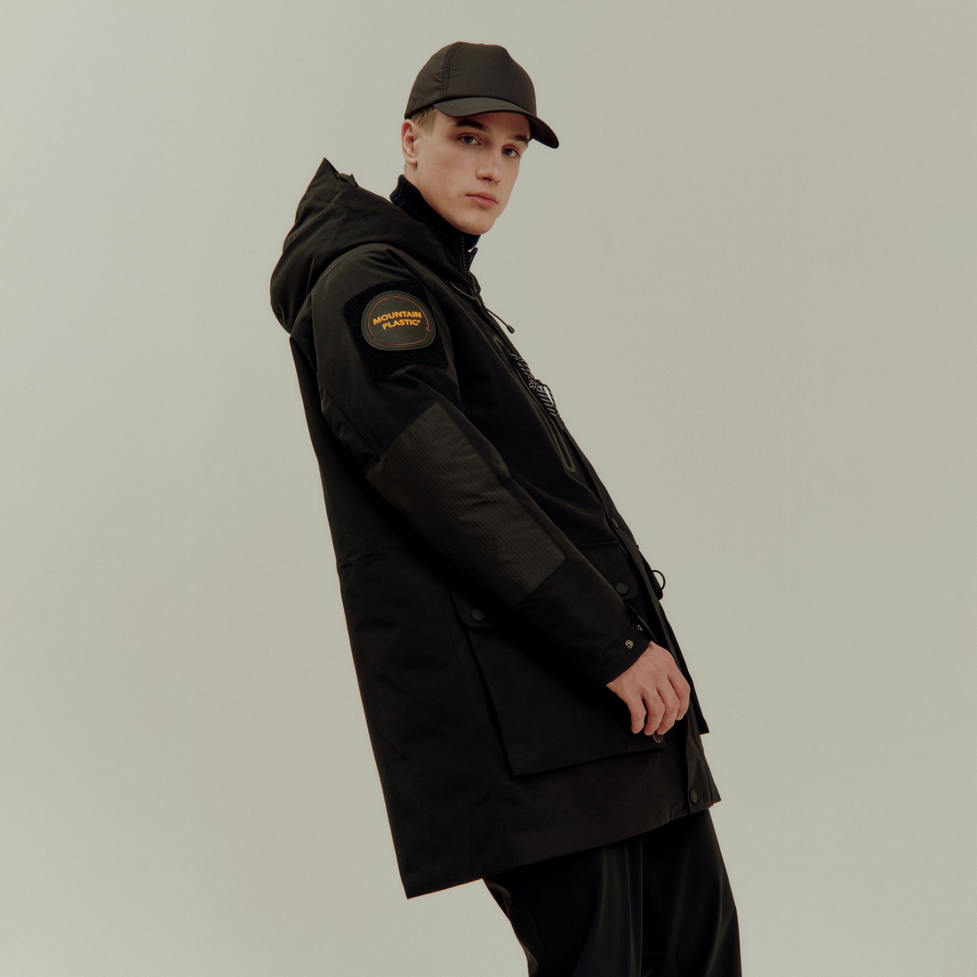 Person wearing a black coat and cap on a plain background