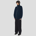 Person standing against a plain background, wearing the Seven Gauge Wool Cotton Full Zip Sweater in Blu, wide-leg pants, and black shoes, with hands by their sides.