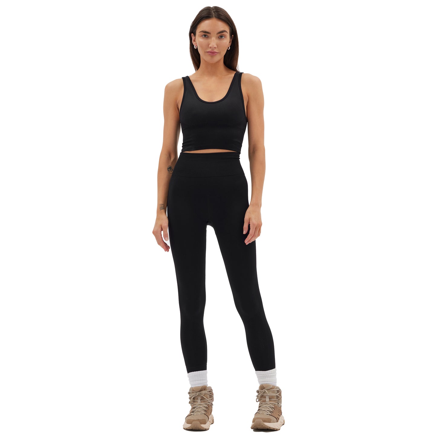 A person stands wearing a black athletic outfit featuring the seamless nylon crop top and Halfdays' Sophia Legging, paired with beige hiking boots and white socks, ready for an outdoor adventure.