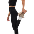 Clad in their Sophia Legging by Halfdays, an individual stretches their leg behind them, holding their foot with one hand, poised for an outdoor adventure.