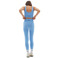 Dressed in a light blue athletic outfit featuring the "Halfdays" logo, a person adjusts their top while facing away. Their seamless nylon Sophia Leggings suggest an outdoor adventure just waiting to unfold.