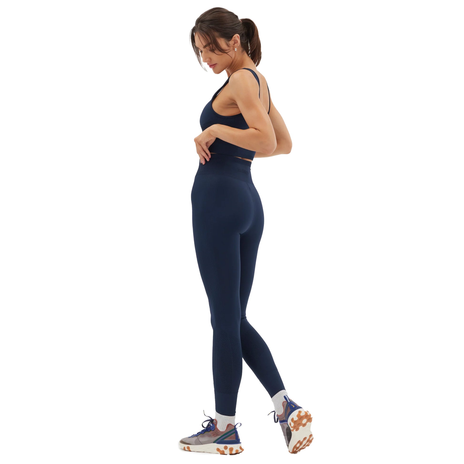 Individual wearing Halfdays' Sophia Legging in navy along with sneakers, standing sideways against a plain white background.