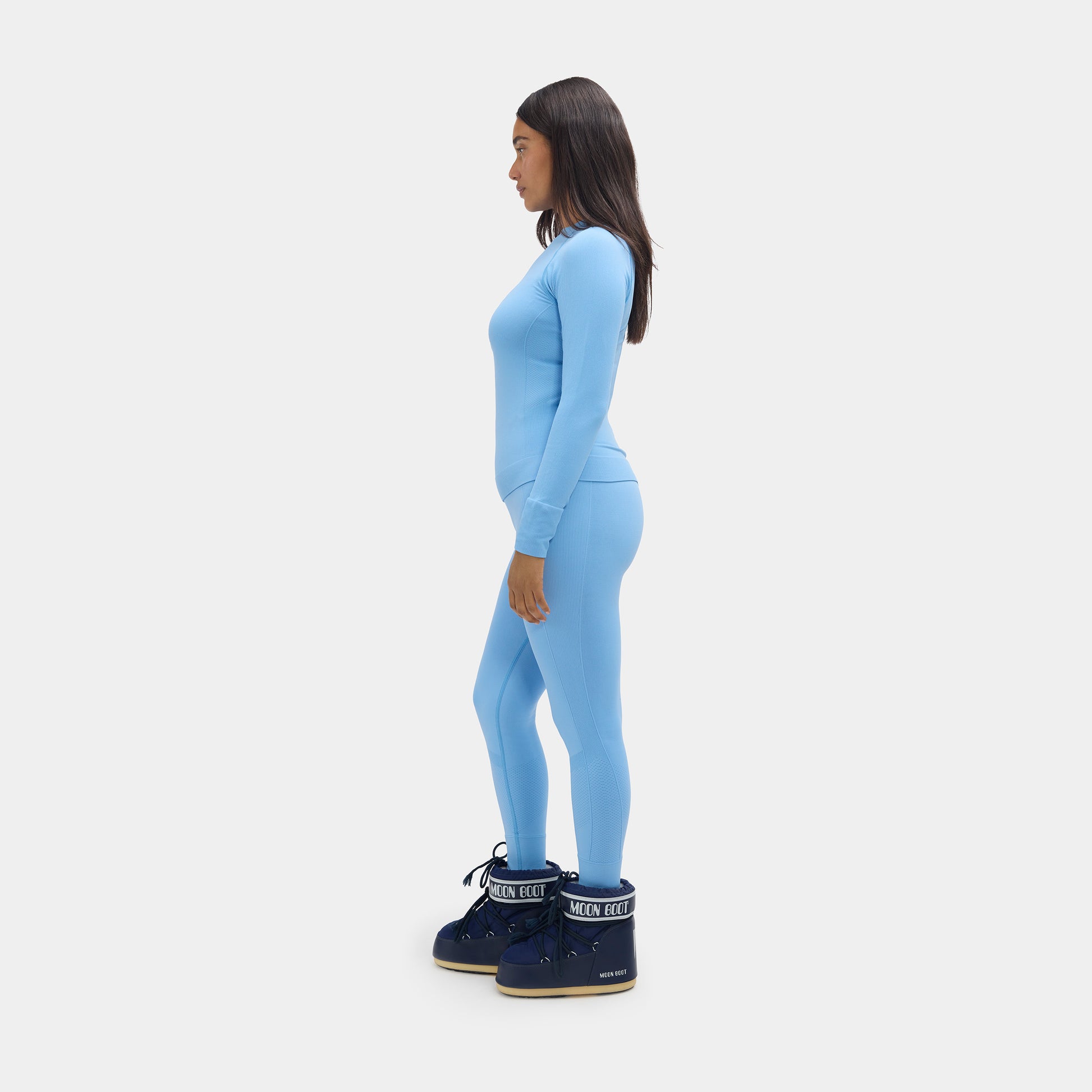 Person wearing a light blue outfit with dark blue boots on a white background