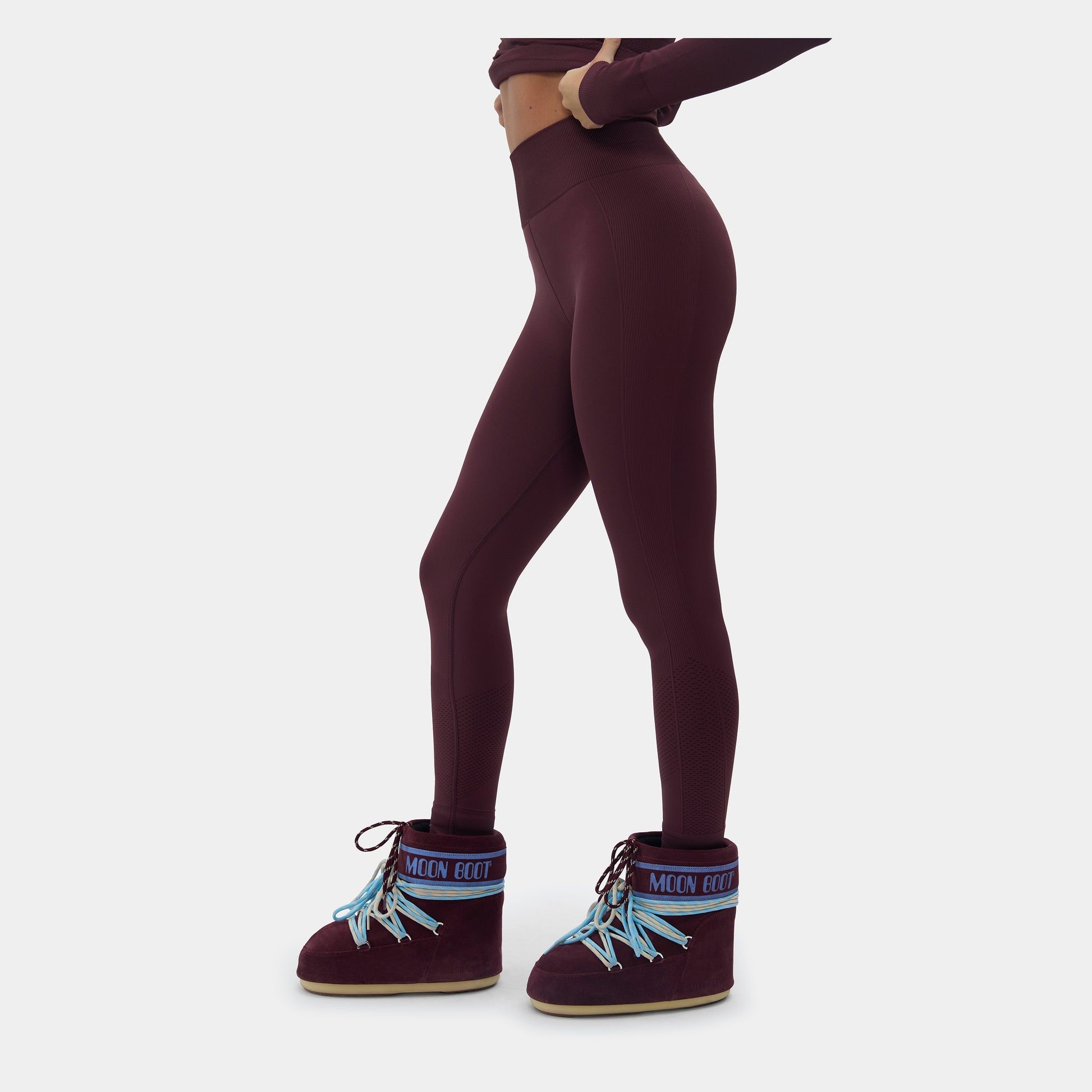 Person wearing maroon leggings and matching boots on a white background