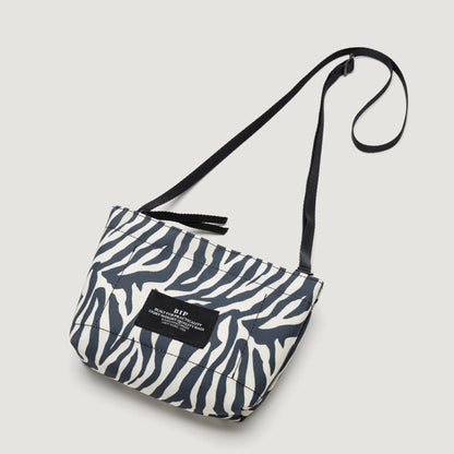 A Bags in Progress Zipper Pouch Mini, Zebra crossbody bag with a black strap, featuring a small label on the front.