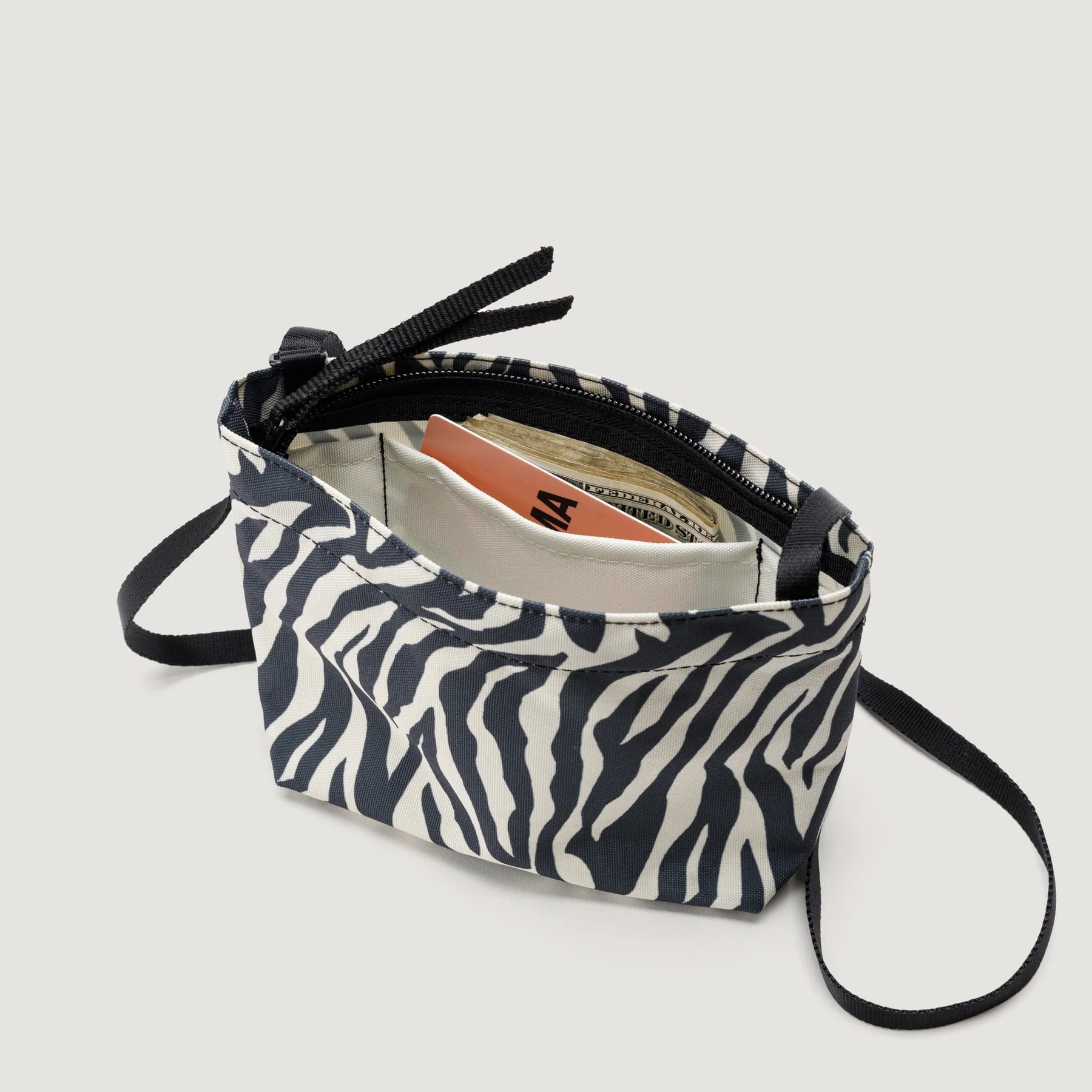 Open Zipper Pouch Mini, Zebra from Bags in Progress with cash and credit cards inside, showing a zippered compartment on a white background.