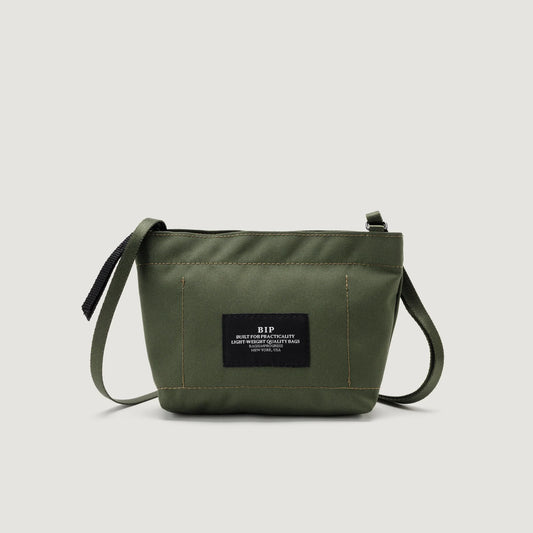 Olive green canvas Zipper Pouch Mini shoulder bag with a black strap, featuring a black label with white text in the center by Bags in Progress.