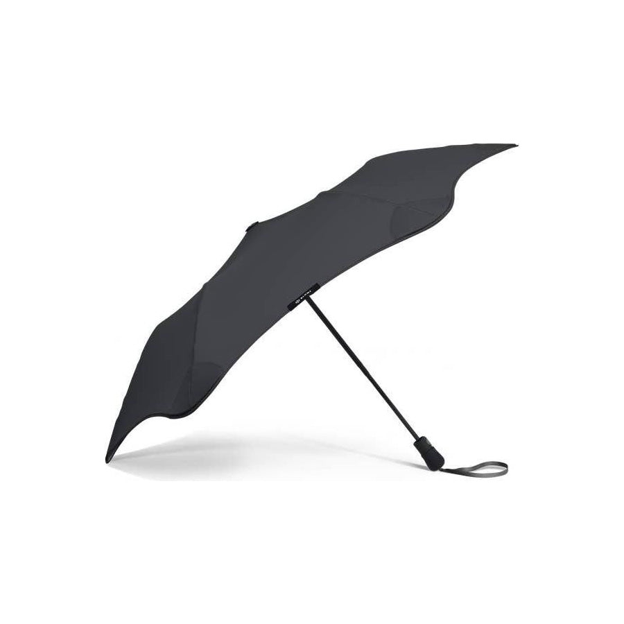 The Blunt Mini Metro Umbrella in black features a curved, asymmetrical canopy, wind-resistant design, and a wrist strap, shown open against a white background.