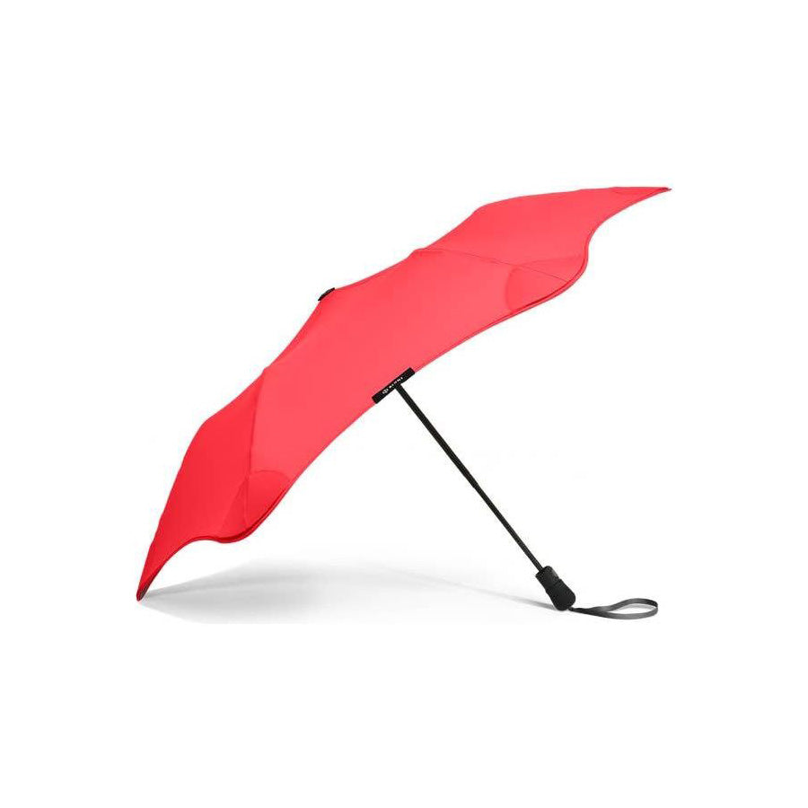The Blunt Mini Metro Umbrella is shown open and tilted, red in color with a black handle and wrist strap, photographed against a white background.