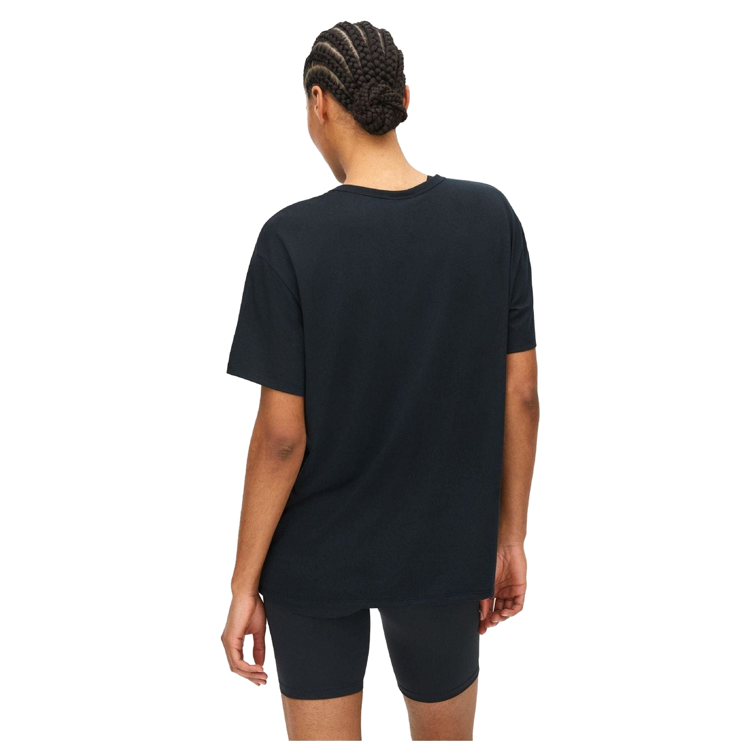 A person, seen from behind against a plain backdrop, wears Rohnisch's Clara Base Tee—a loose silhouette black t-shirt made from recycled polyester—and black shorts.