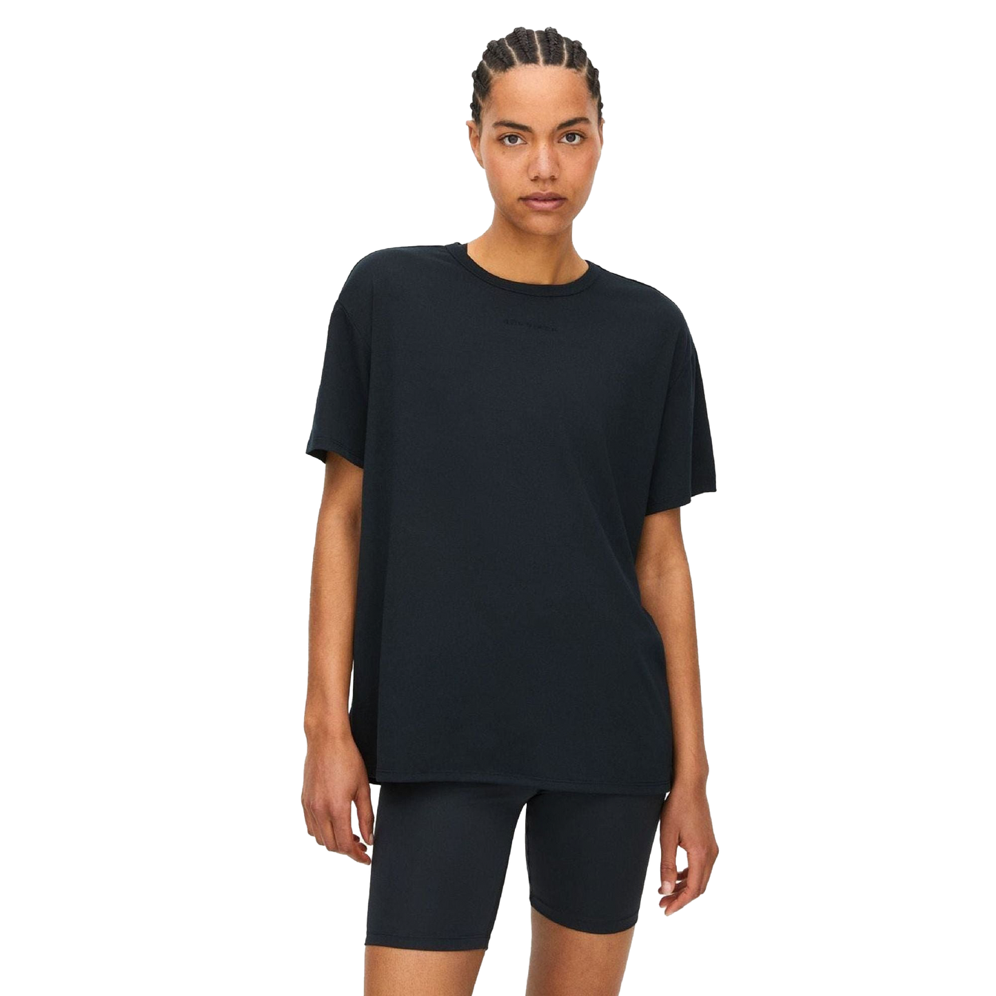 A person in a black Clara Base Tee and loose-fitting shorts stands against a transparent background, highlighting Rohnisch's latest blend of recycled polyester and elastane for ultimate comfort.