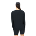 A person, viewed from behind, is wearing Rohnisch's Clara Base LS, a black long-sleeve shirt paired with a black cap and shorts. All items are made from recycled polyester.