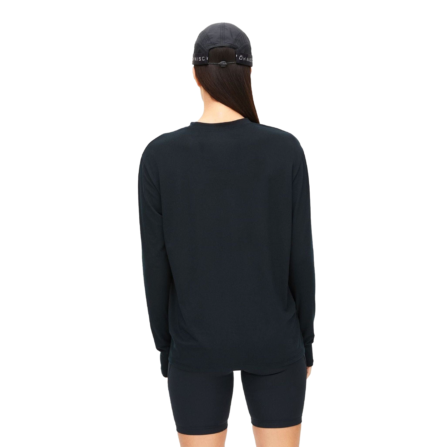 A person, viewed from behind, is wearing Rohnisch's Clara Base LS, a black long-sleeve shirt paired with a black cap and shorts. All items are made from recycled polyester.