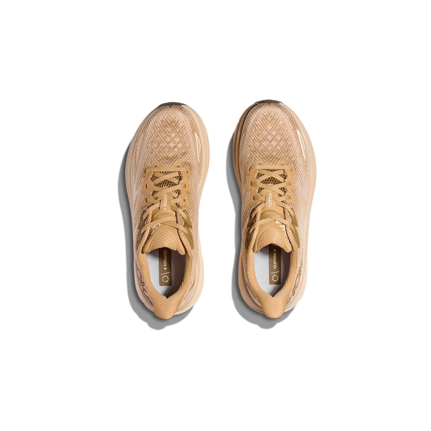 A pair of Hoka M Clifton 9 athletic shoes in Wheat/Shifting Sand, shown from above side by side on a white background, featuring responsive toe-off and exceptional cushioning.