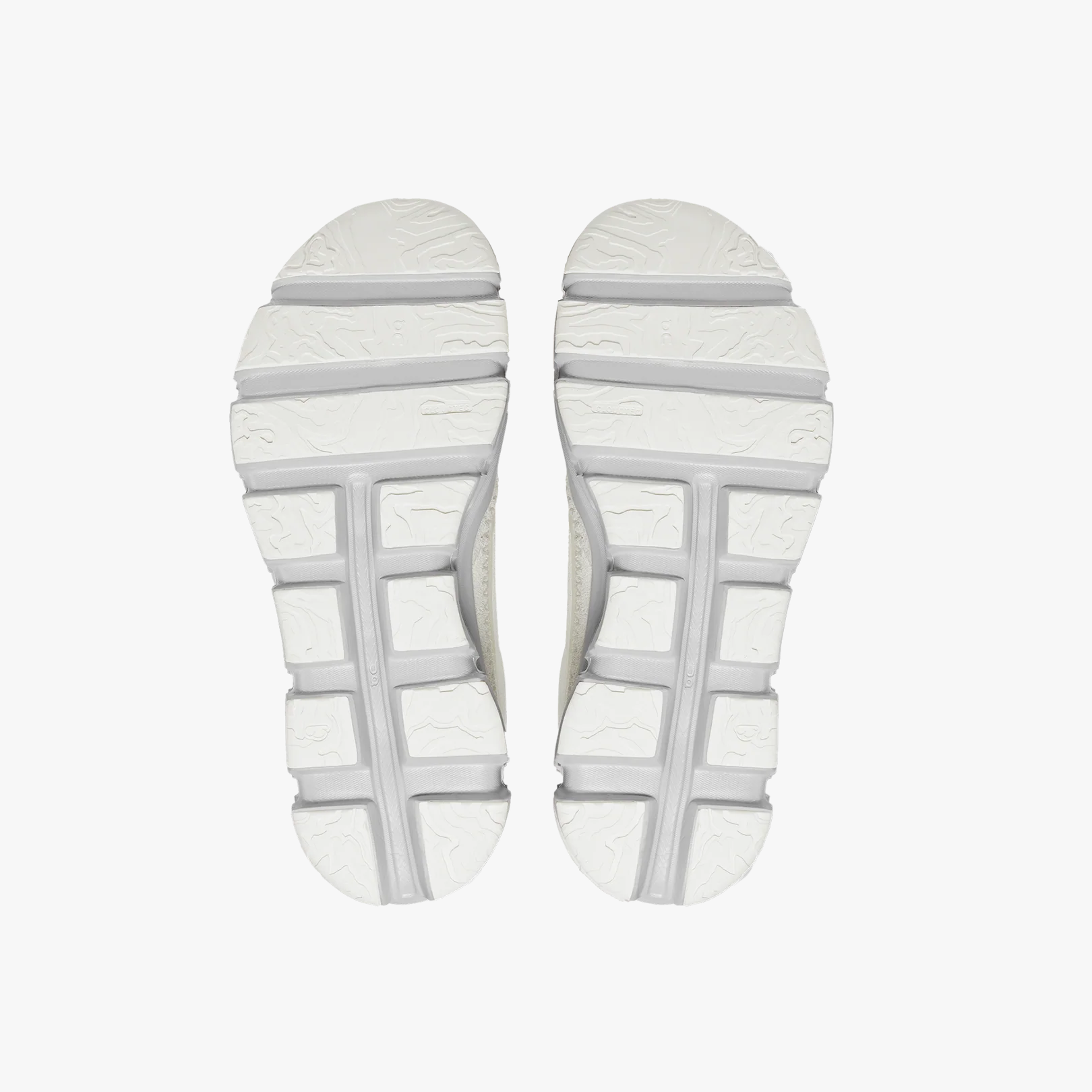Overhead view of the white textured CloudTec soles on the Women's Cloudaway athletic shoes by On Running, highlighting grooves and patterns for traction against a plain white background.