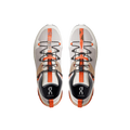 The Men’s Cloudtrax by On Running are gray and orange athletic shoes with black laces, crafted from recycled polyester, showcased from above against a black background.
