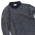 The Nordsjo Crew Neck by Devold is a navy and white patterned knit sweater made of Norwegian wool. It features a ribbed collar, small teardrop designs, and offers unisex fit versatility with a text label inside.