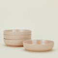 A stack of four Essential Low Bowls by Hawkins New York sits beside a single matching bowl; all are dishwasher and microwave safe.