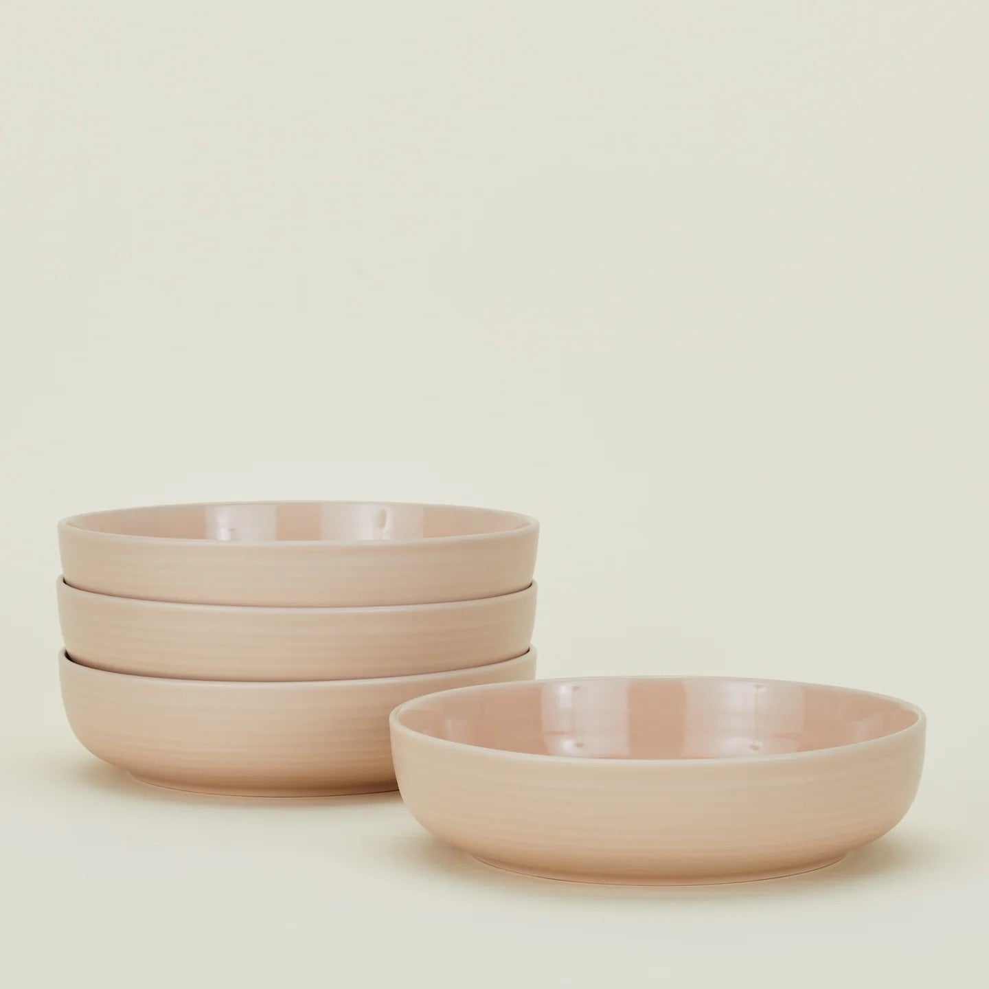 A stack of four Essential Low Bowls by Hawkins New York sits beside a single matching bowl; all are dishwasher and microwave safe.