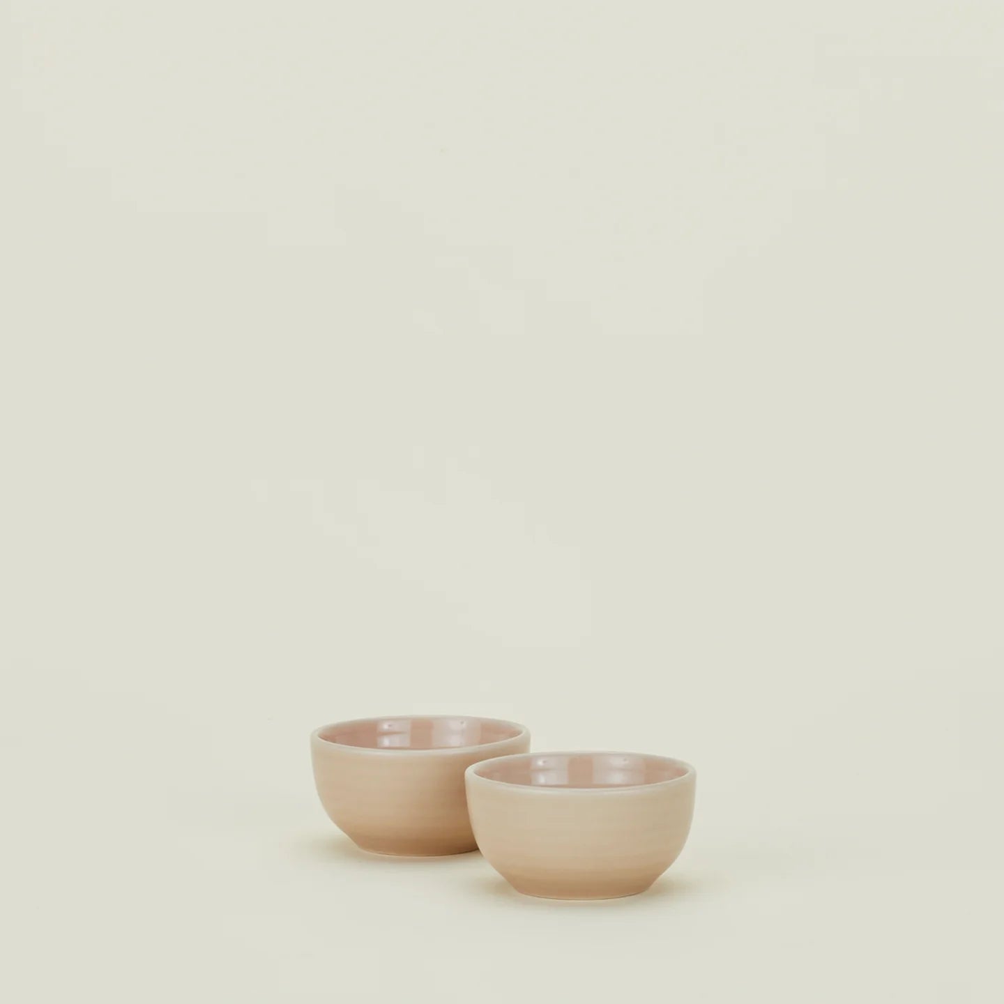 Two blush ceramic bowls from Hawkins New York's Essential Extra Small Bowl set sit side by side on a light surface against a plain background.