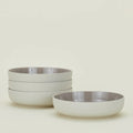 The Hawkins New York Essential Low Bowl set includes four dishwasher- and microwave-safe stoneware bowls with a glossy interior, pictured with three stacked left and one on the right against a plain light background.