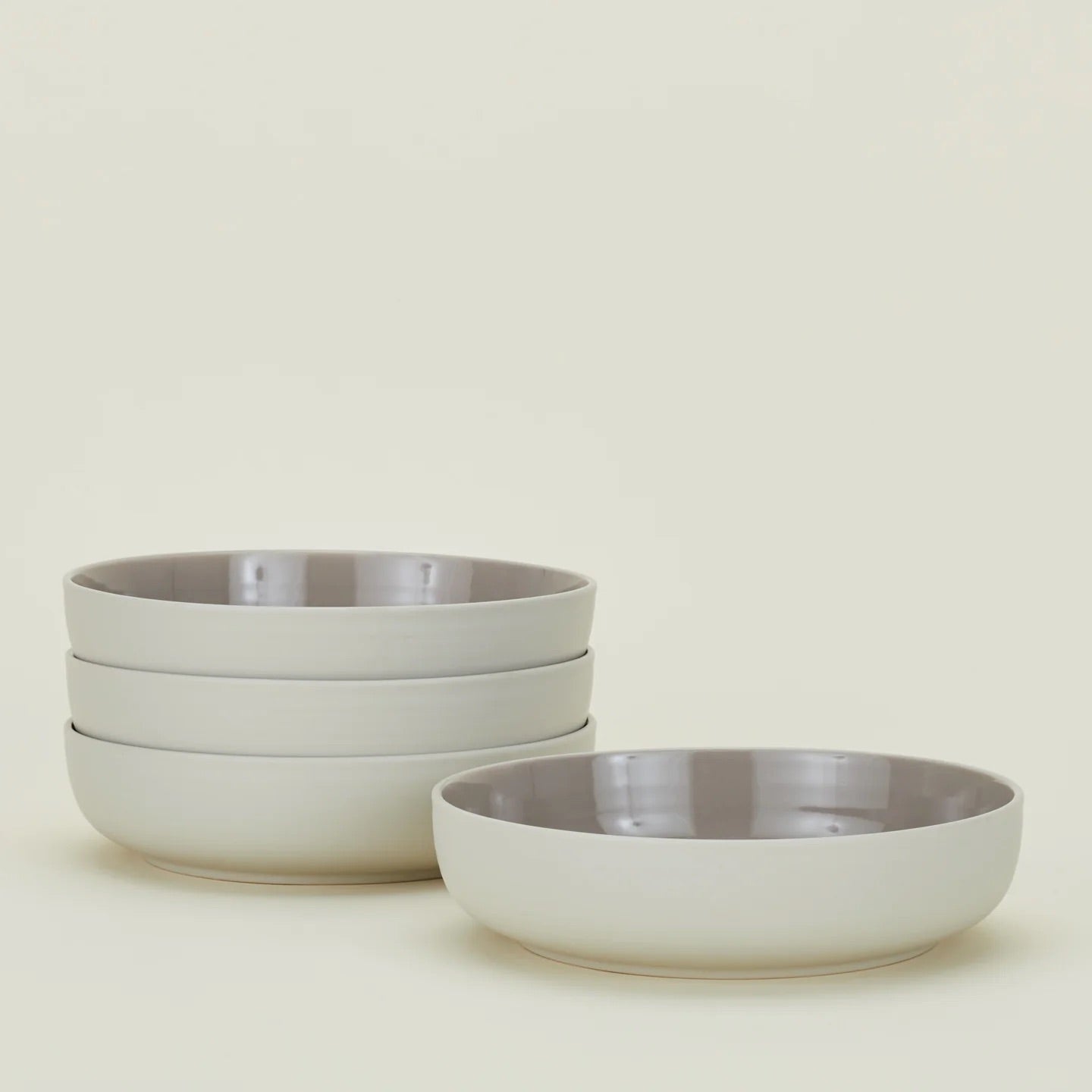 The Hawkins New York Essential Low Bowl set includes four dishwasher- and microwave-safe stoneware bowls with a glossy interior, pictured with three stacked left and one on the right against a plain light background.