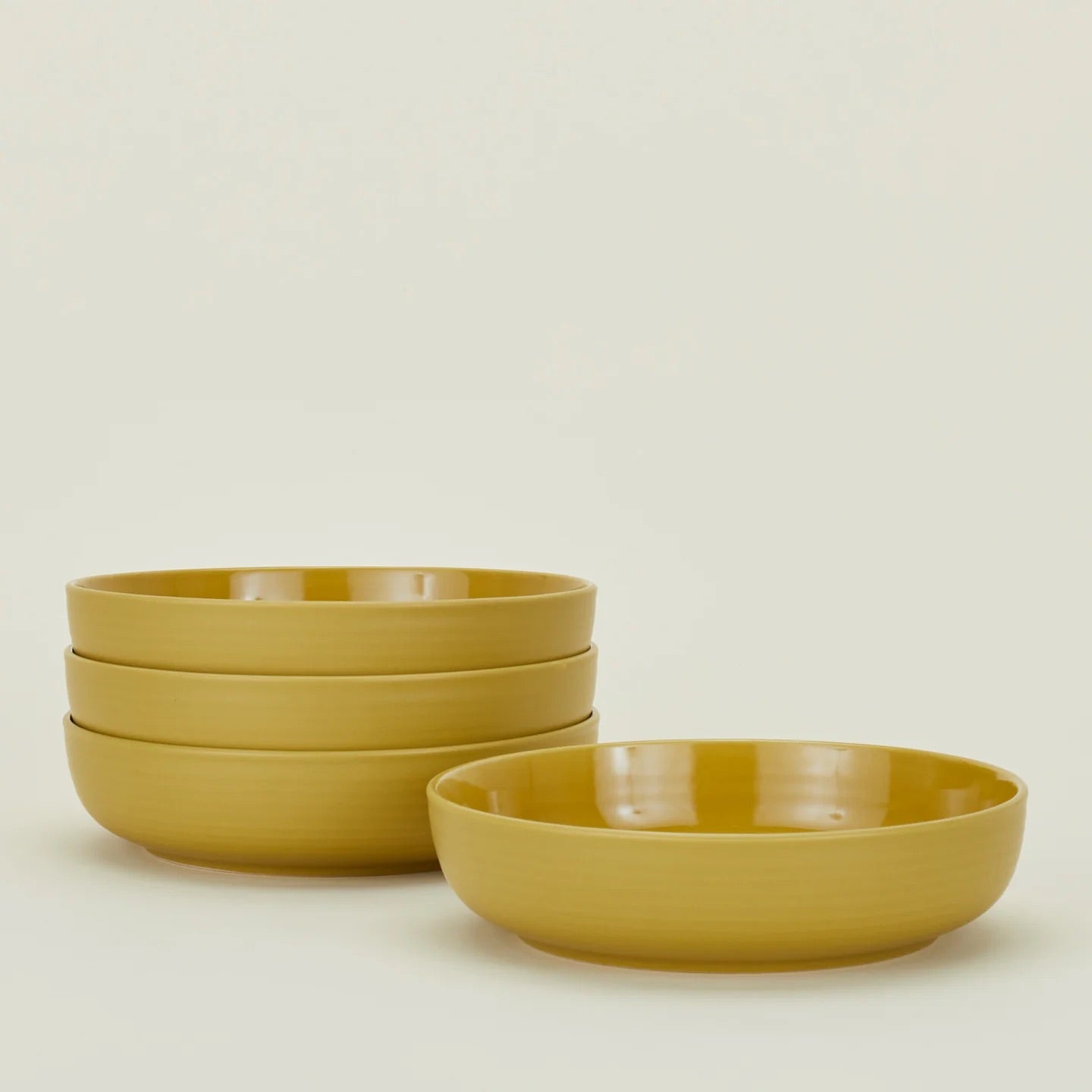 The Hawkins New York Essential Low Bowl (Set of 4) pairs style and function—four mustard-yellow stoneware bowls are both dishwasher and microwave safe, making them perfect for modern dining.