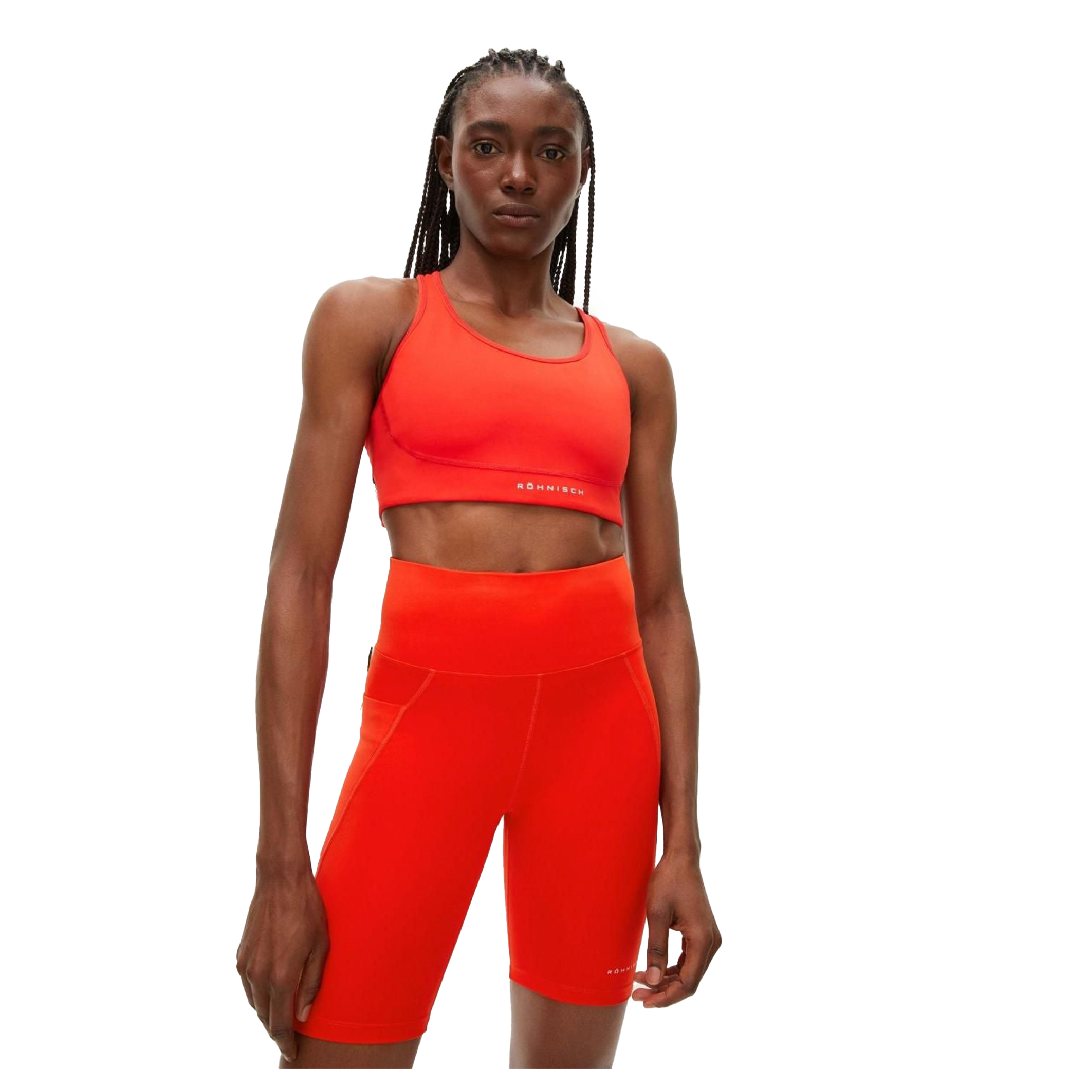 A person wearing Rohnisch’s eye-catching Flattering High Waist Bike Tights, along with a matching bright red sports bra made from breathable fabric, looks directly at the camera.