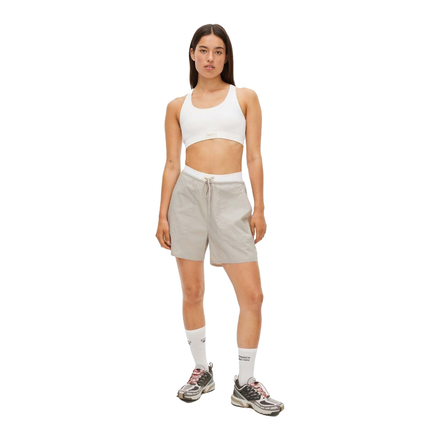 A person in a white crop top, light gray Frankie Wind Shorts by Rohnisch, high white socks, and sneakers with the Rohnisch logo stands against a plain background.