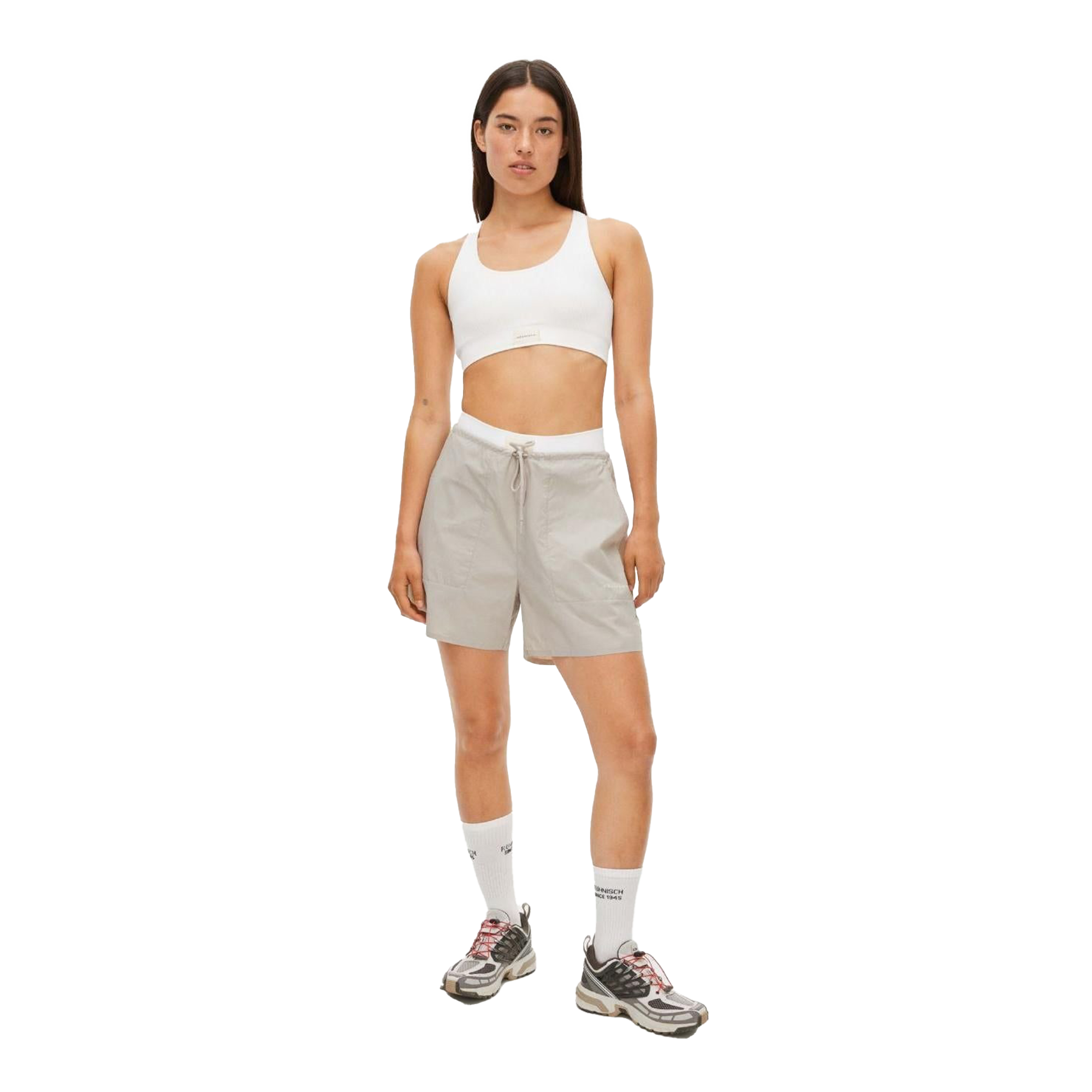 A person in a white crop top, light gray Frankie Wind Shorts by Rohnisch, high white socks, and sneakers with the Rohnisch logo stands against a plain background.