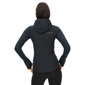 A person wearing the Free Motion Padded Jacket, a dark hooded jacket from Rohnisch made of quilted woven polyester, stands with their back to the camera, hands on hips.