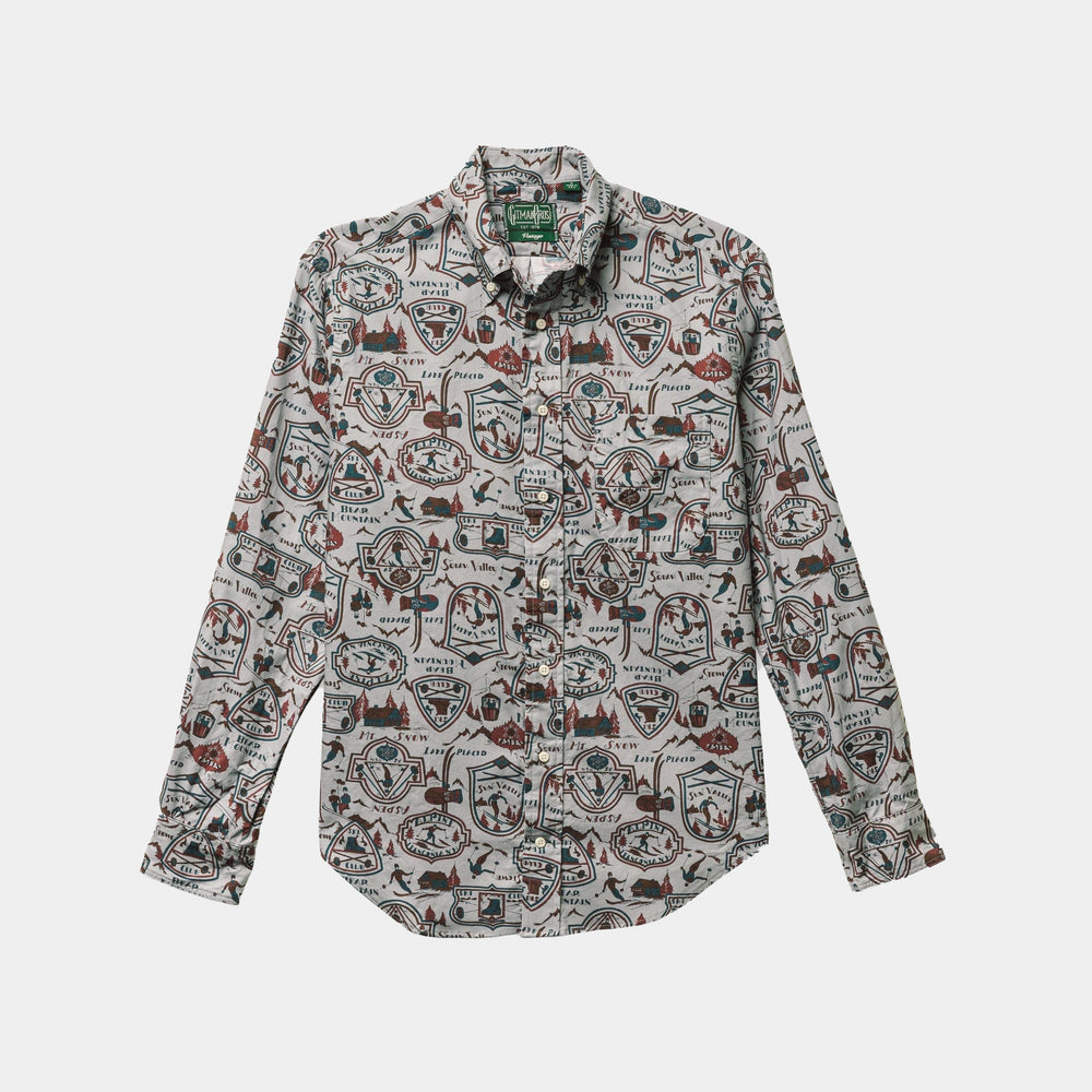 The Ski Club Print, Grey Pattern shirt by Gitman Vintage is a long-sleeve, button-up with a lively print of badges, shapes, and outdoor graphics on a light background.