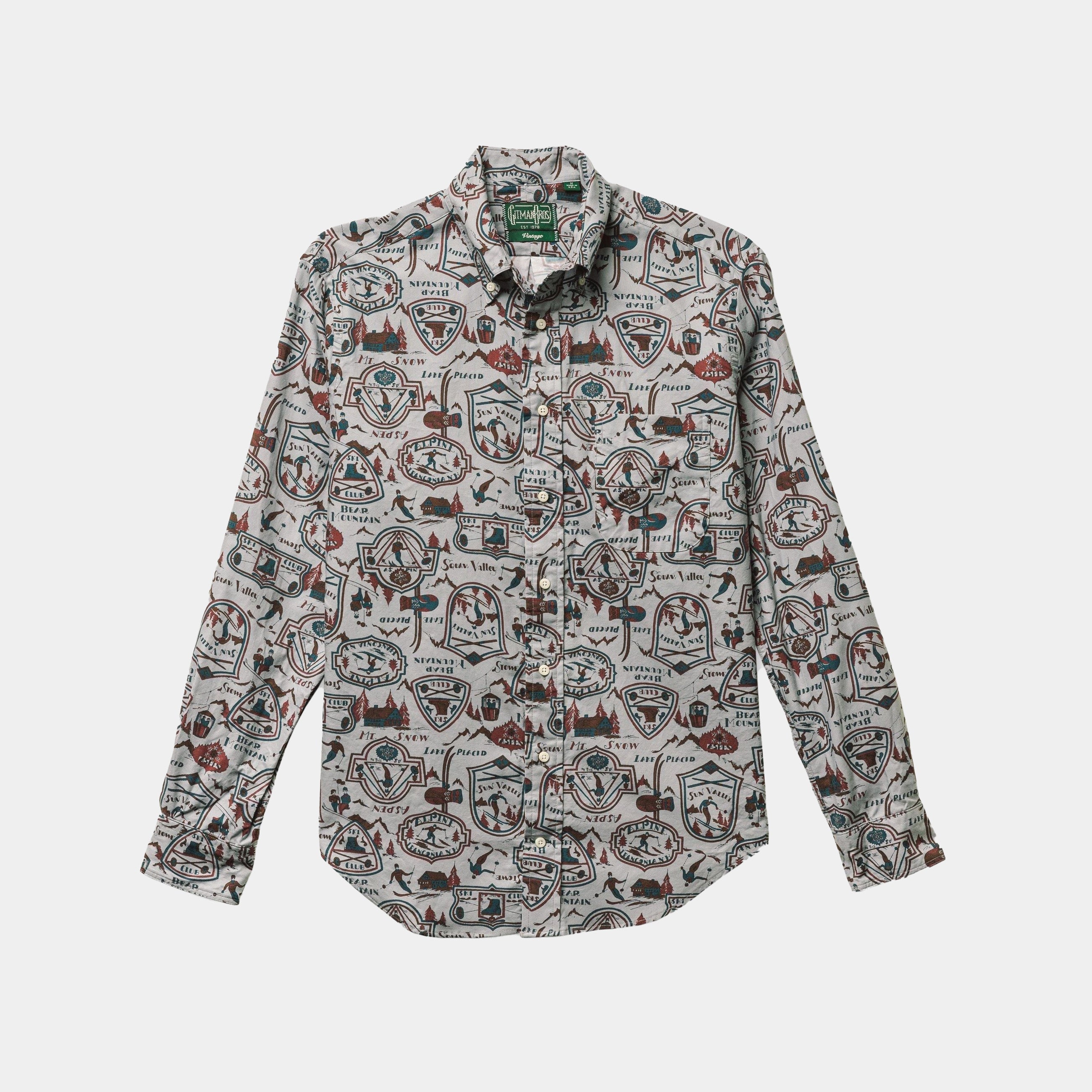The Ski Club Print, Grey Pattern shirt by Gitman Vintage is a long-sleeve, button-up with a lively print of badges, shapes, and outdoor graphics on a light background.