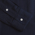 Close-up of the Gitman Vintage Overdye Seersucker Shirt in Navy, featuring a textured dark blue sleeve with two white buttons and visible stitching.