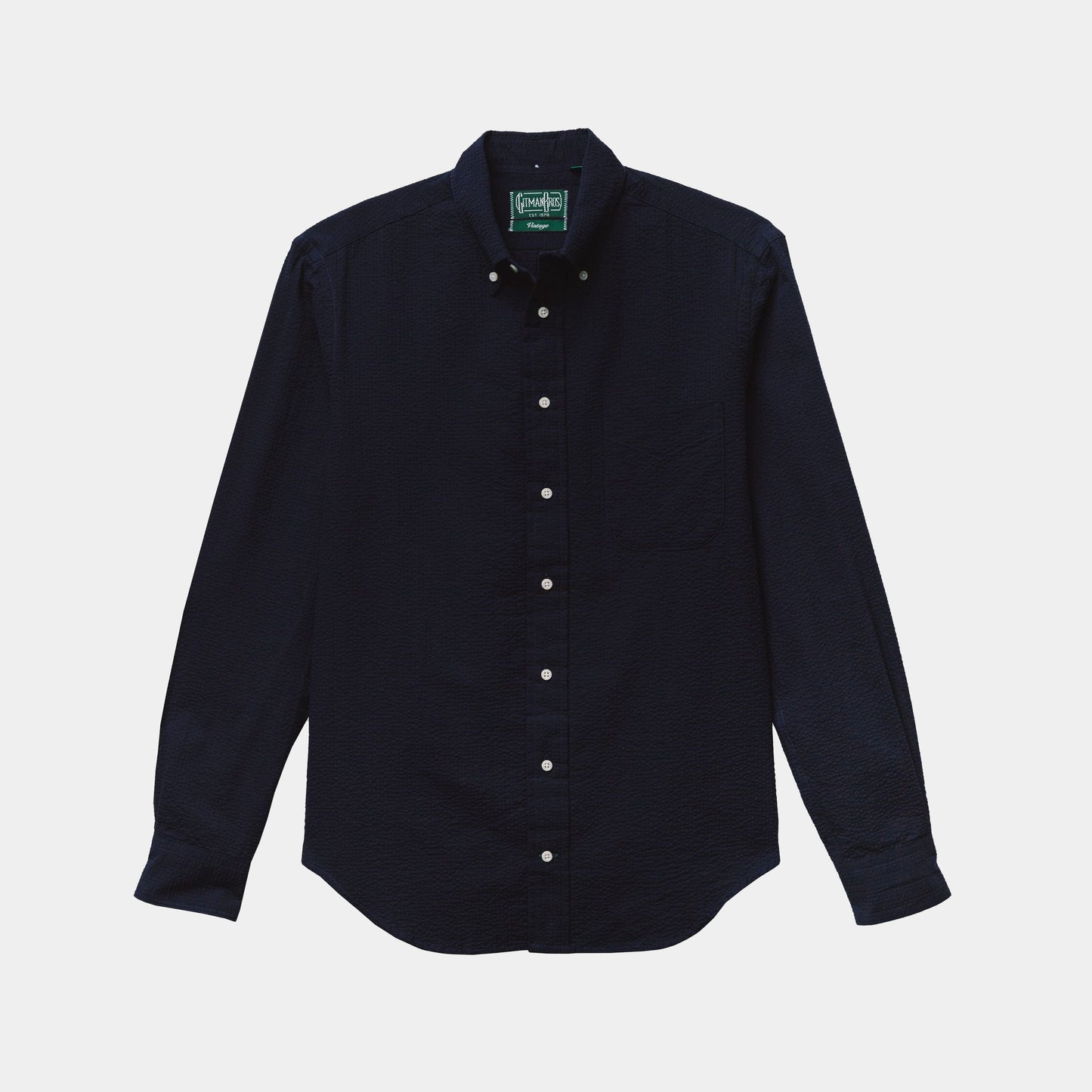 The Gitman Vintage Overdye Seersucker Shirt in Navy, a long-sleeve button-up with a collar and white buttons, is laid flat on a light background.