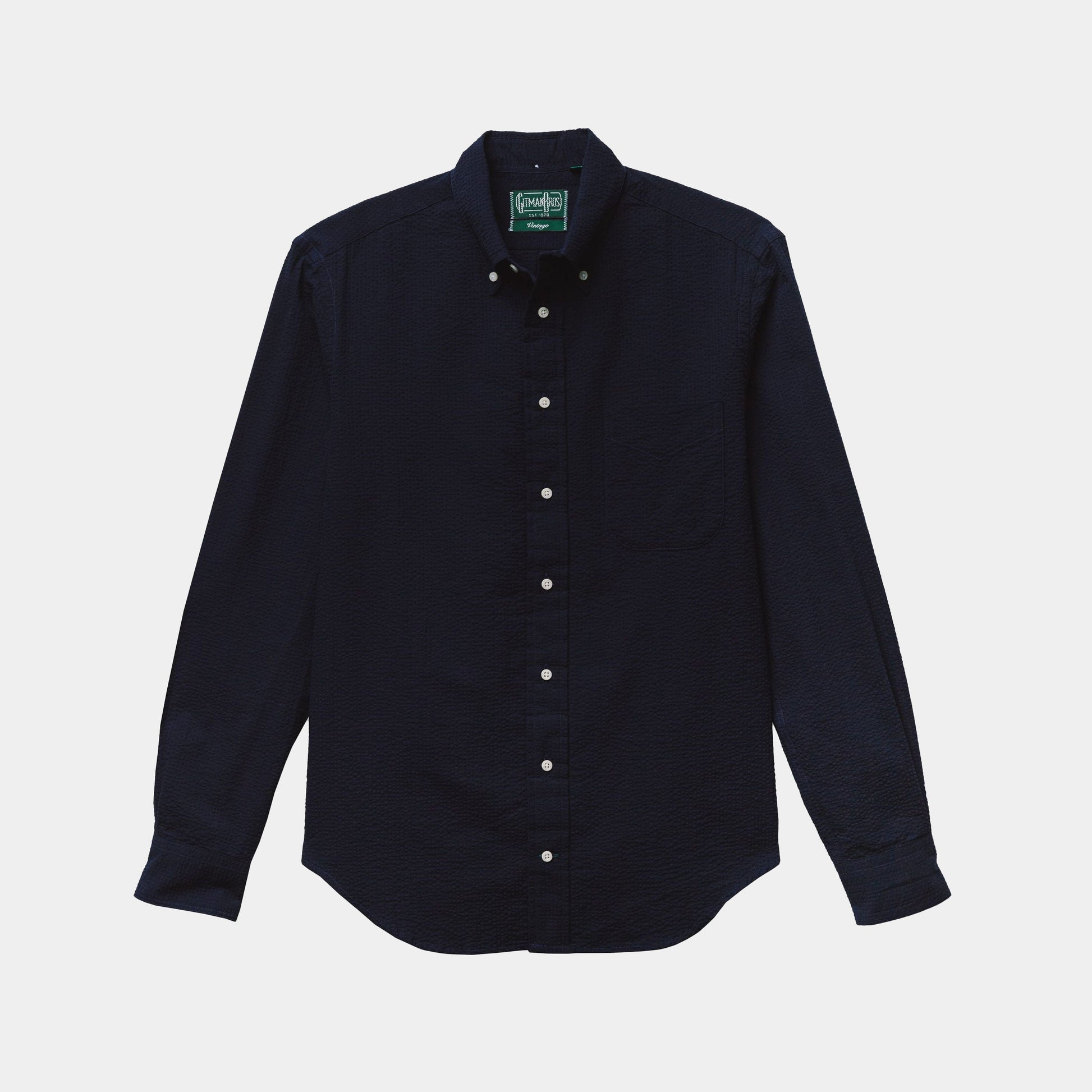 The Gitman Vintage Overdye Seersucker Shirt in Navy, a long-sleeve button-up with a collar and white buttons, is laid flat on a light background.