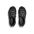 The Hoka U Ora Primo sneakers, in black, feature gray-green crisscross laces and insulated puff uppers for slip-on comfort. Set against a plain white background, these shoes offer style and recovery with every step.