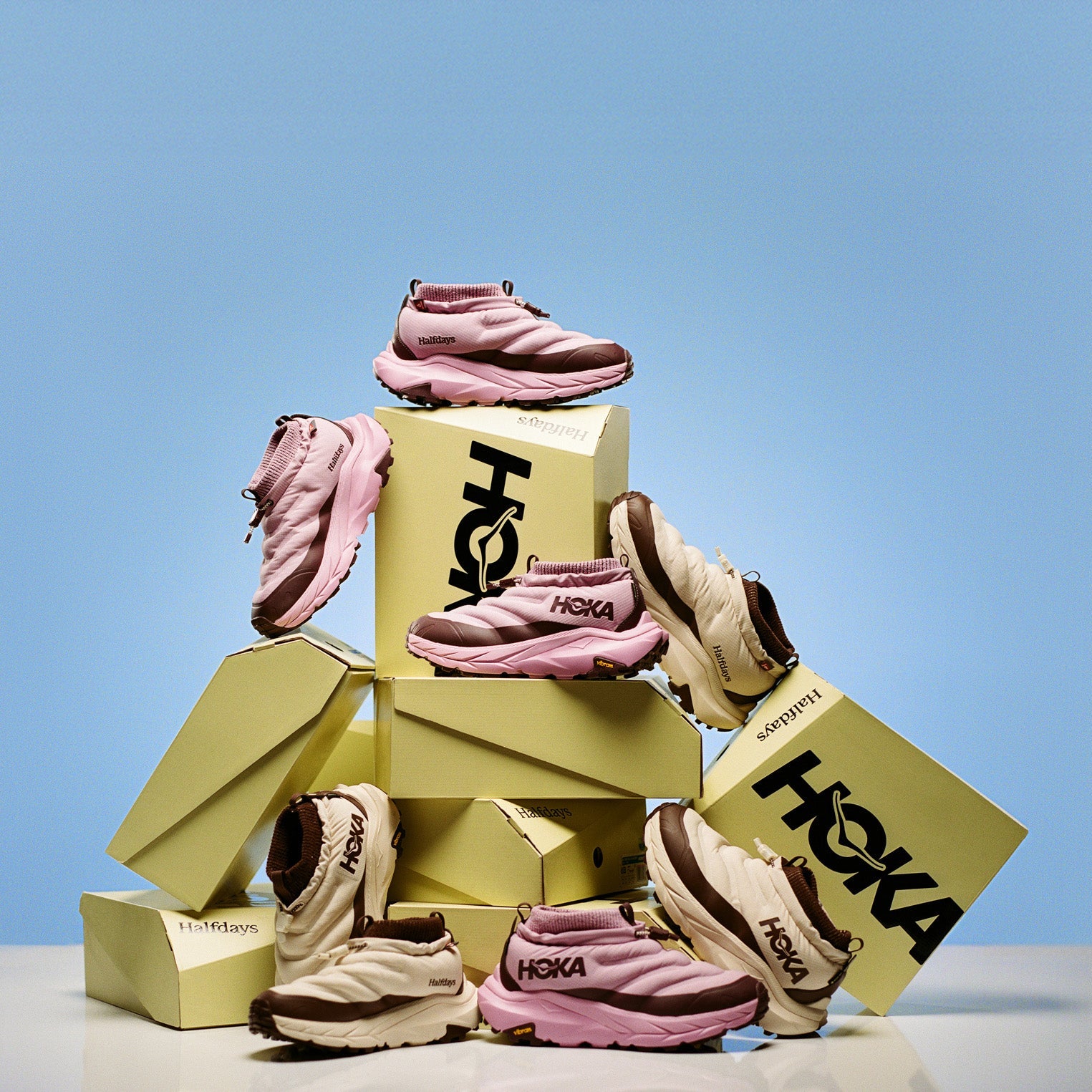 Three shoes stacked on top of each other with 'Hoka' branding against a blue background