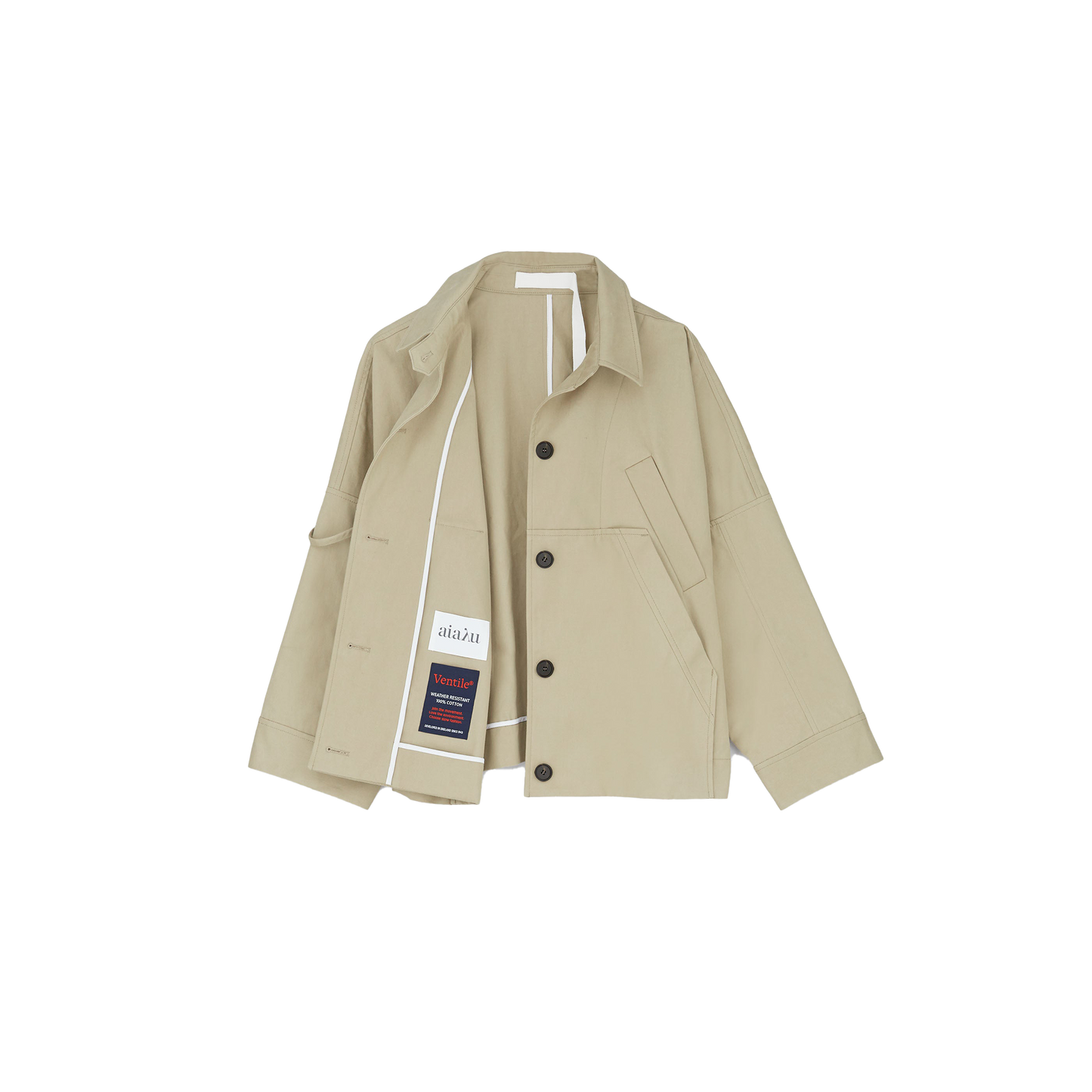 The Jules Jacket by Aiayu is displayed against a white background, featuring a beige design with large black buttons, crafted from weather-resistant Ventile fabric. It includes a left-side pocket and visible inner labels.