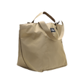 The Large Double Handle Tote by Bags in Progress is a beige tote crafted from woven nylon, featuring a black label, double handles, and an adjustable shoulder strap.