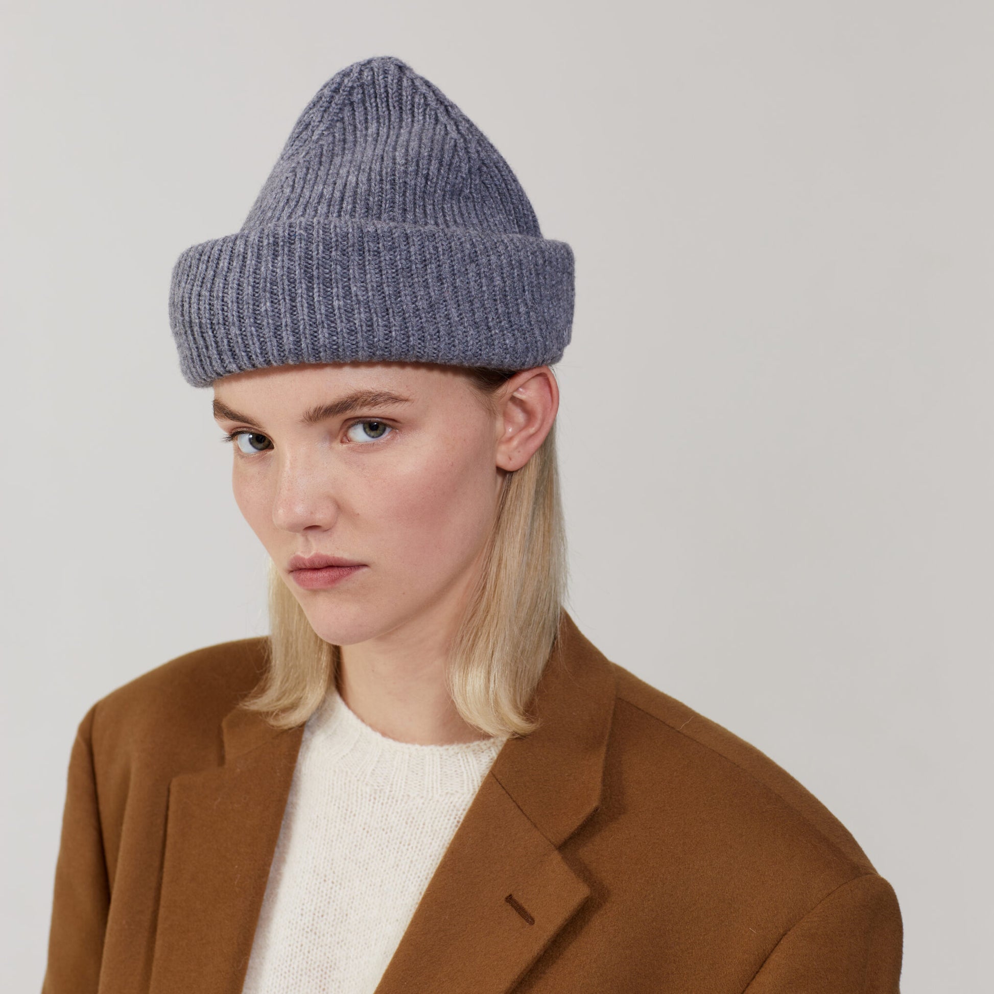 Person in a brown coat and white shirt wearing a Le Bonnet Smoke Balaclava, looking directly at the camera.