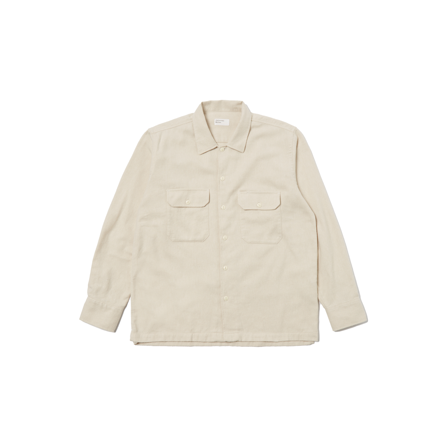 A Universal Works LS Utility Shirt in beige, made from 100% cotton, showcases long sleeves and button flap chest pockets while laid flat against a black background.