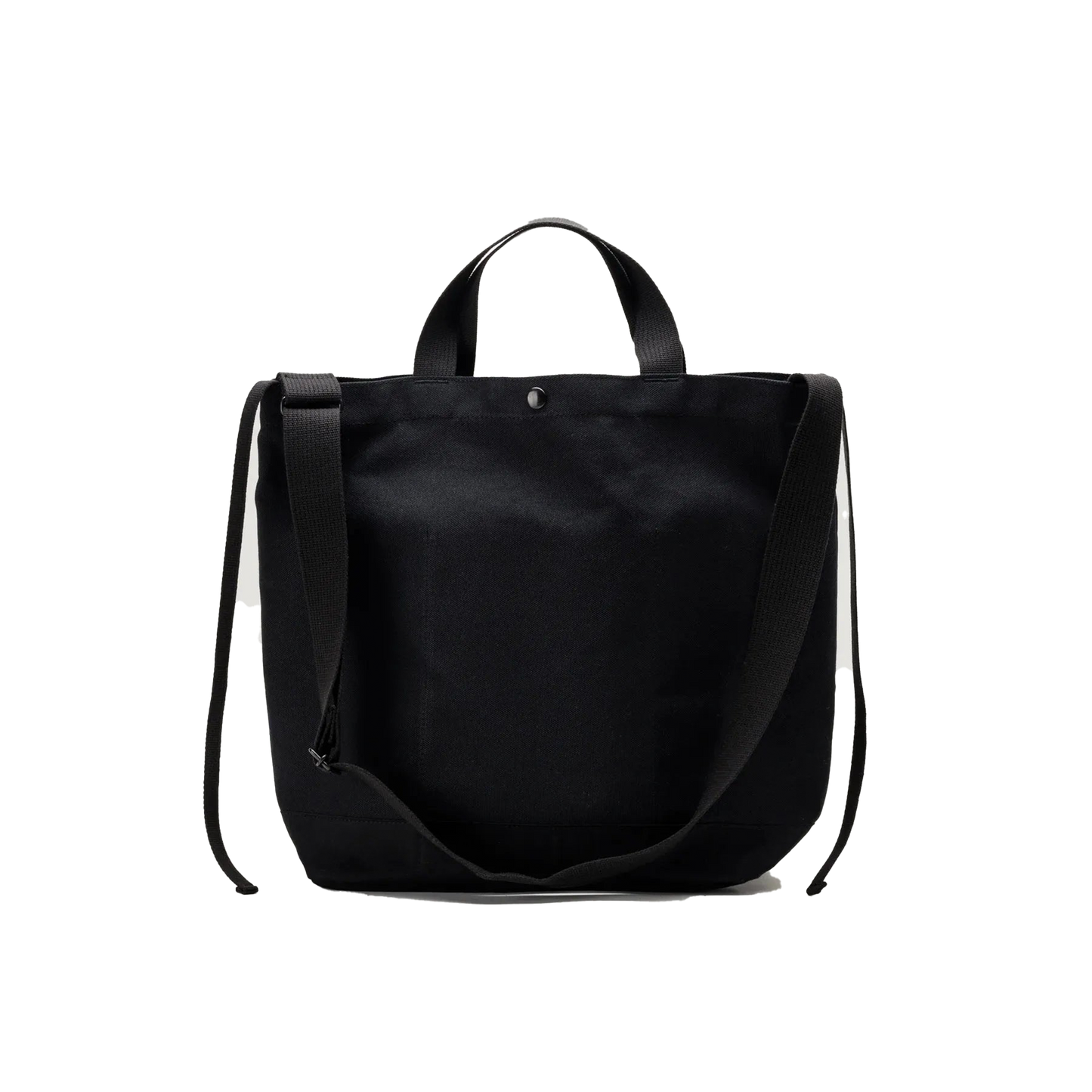 The Bags in Progress New York Tote Medium is a black cotton canvas bag made in Japan, featuring two short handles and a long adjustable shoulder strap, displayed against a white background.