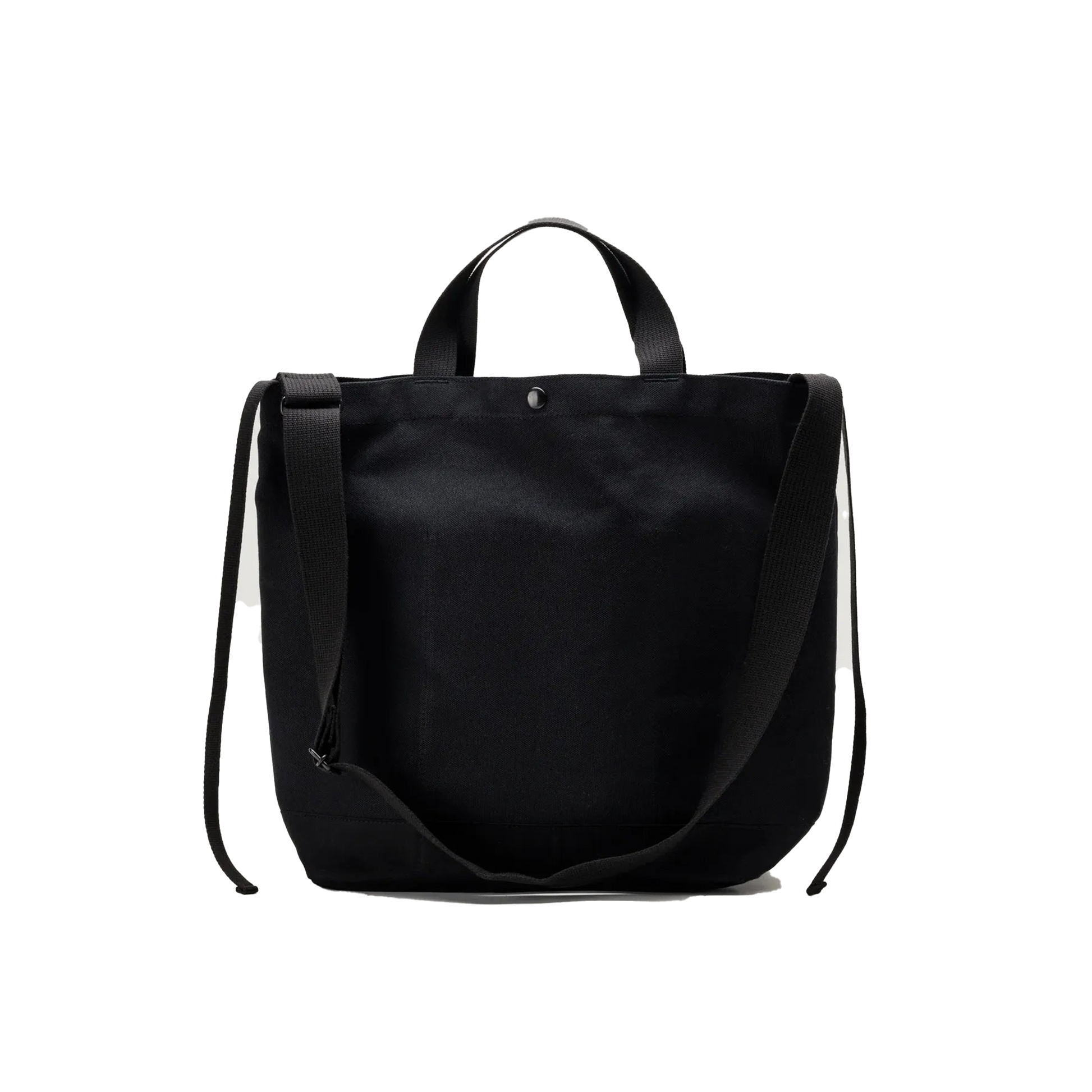 The Bags in Progress New York Tote Medium is a black cotton canvas bag made in Japan, featuring two short handles and a long adjustable shoulder strap, displayed against a white background.