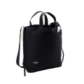 The Bags in Progress New York Tote Medium is a black cotton canvas bag made in Japan, with dual handles, an adjustable shoulder strap, a small white front label, and a document partially visible in the side pocket.