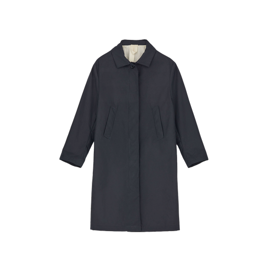The Noor Coat Oil by Aiayu is a long, dark classic coat made from wax-coated organic cotton, featuring a classic collar and two front pockets, displayed on a plain background.