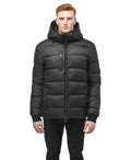 Oliver, in the Nobis Oliver Men's Reversible Puffer Jacket paired with black jeans, effortlessly transitions from day to night against a crisp white backdrop.